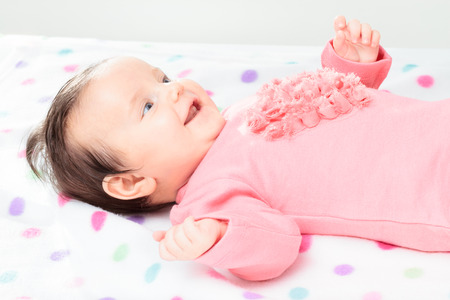 Smiling little baby girl lying on polka dots blanketの写真素材
