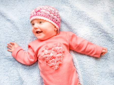 Happy smiling baby girl lying on blue blanketの写真素材