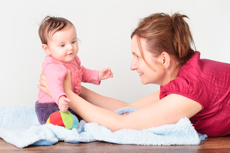 Woman lying on the floor and playing with her little baby girlの写真素材