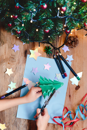 Girl making Christmas tree decoration from paperの写真素材