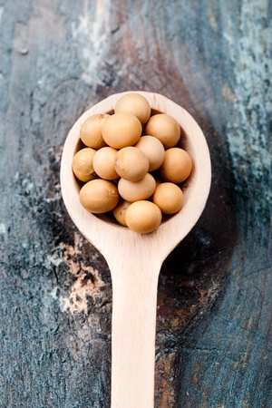 Soya beans on wooden spoon and wooden tableの写真素材