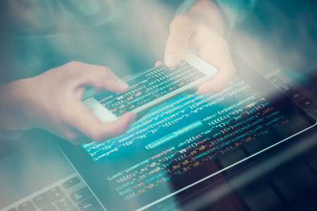 Hacker using computer, smartphone and coding to steal password and private data remotely from car. Screen displaying program code, website development, application building, password and private dataの写真素材