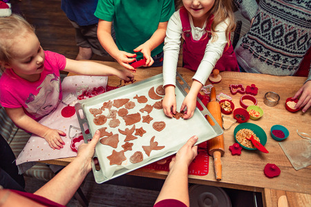 Baking Christmas cookies. Christmas gingerbread cookies in many shapes decorated with colorful frosting, sprinkle, icing, chocolate coating, toppers, put on table.の写真素材