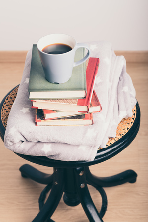 A few books with cup of coffee and blanket on wooden chairの写真素材