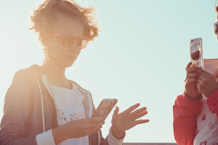 Young girl and her mother taking a photos over sea during summer vacation using smartphone camera enjoying sunny summertime dayの写真素材
