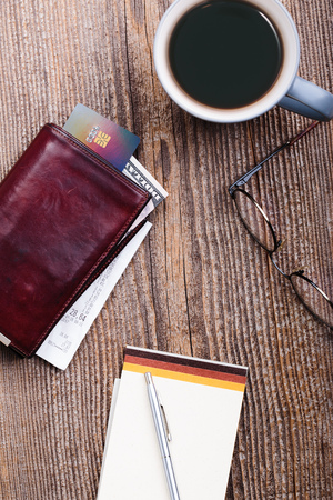 Leather wallet with dollar banknotes, credit card and receipt, glasses, cup of coffee on wooden desk. Portrait orientationの写真素材