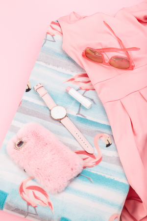 Female pink dress, mobile phone in pink case, watch with pink stripe on pink backgroundの写真素材