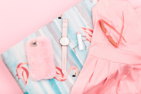 Female pink dress, mobile phone in pink case, watch with pink stripe on pink backgroundの写真素材