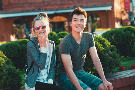 Couple of friends, teenage girl and boy,  having fun together, sitting in center of town, spending time togetherの写真素材