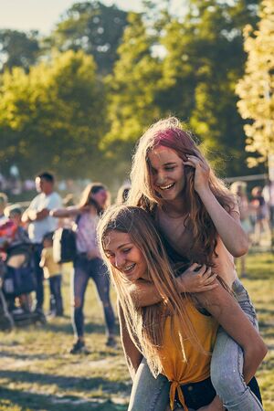 Portrait of happy smiling young girls with colorful paints on faces and clothes. Two friends spending time on holi color festivalの写真素材