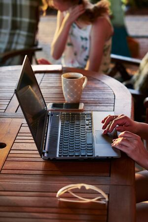 Woman working at home, using portable computer, sitting on patio on summer dayの写真素材