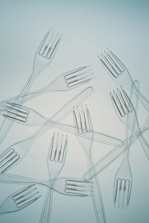 Scattered plastic forks over blue background. Collecting plastic waste to recycling. Concept of...