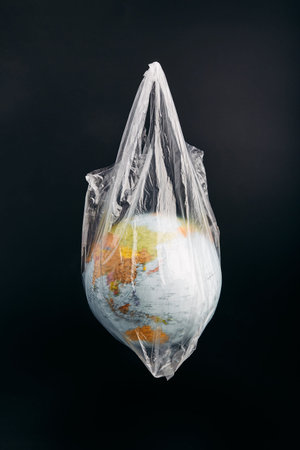 Globe in a plastic bag. Earth contaminated by plastic waste. Concept of plastic pollution and...