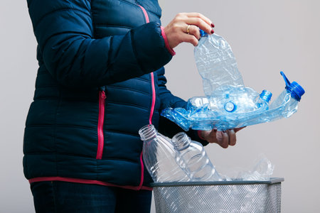 Woman throwing out used plastic bottles and packagings in trash bin. Collecting empty plastic...
