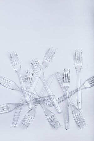 Plastic forks scattered over white background. Collecting plastic waste to recycling. Concept of plastic pollution and too many plastic waste. Copy space at the topの写真素材