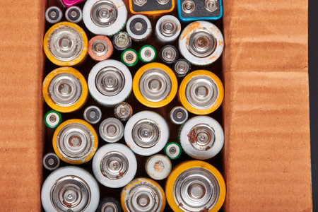 Discharged batteries in cardboard box. Collecting used batteries to recycle. Waste disposal and...