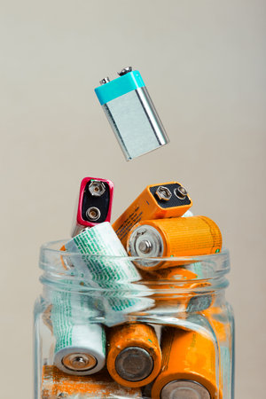 Used battery falling into a jar filled with discharged batteries. Waste disposal and recycling. Copy...