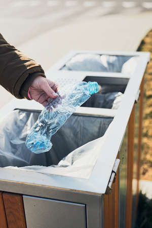 Woman throwing a plastic bottle to trash. Plastic waste to recycling. Concept of plastic pollution and recycling plastic waste. Environmental issue. Environmental damage. Real people, authentic situationsの写真素材