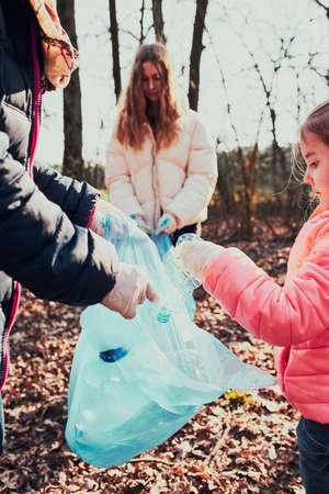 Family cleaning up a forest. Volunteers picking plastic waste to bags. Concept of plastic pollution and too many plastic waste. Environmental issue. Environmental damage. Responsibilitiy for environment. Real people, authentic situationsの写真素材