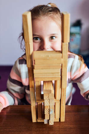 Little girl preschooler playing with wooden blocks toy building a tower. Concept of building a houseの写真素材