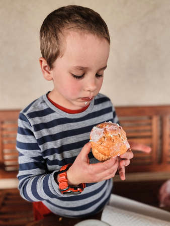 Boy enjoying eating sweet tasty cupcake that you she made herself at homeの写真素材