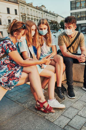 Family spending time together sitting in the city center. Girls wearing the face masks to avoid virus infection and to prevent the spread of disease in time of coronavirusの写真素材