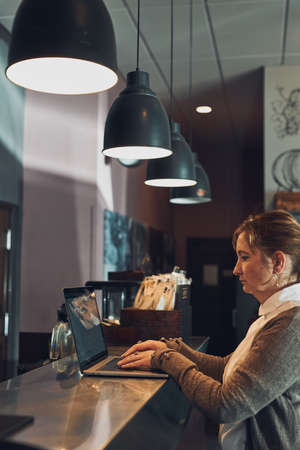 Focused businesswoman working remotely on her laptop computer contemplate managing her work sitting at the table in a cafeの写真素材