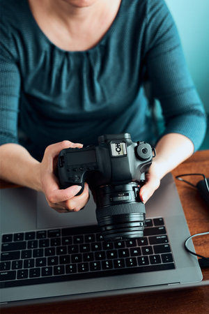 Female photographer working on photos on laptop and camera. Woman editing retouching browsing photos...