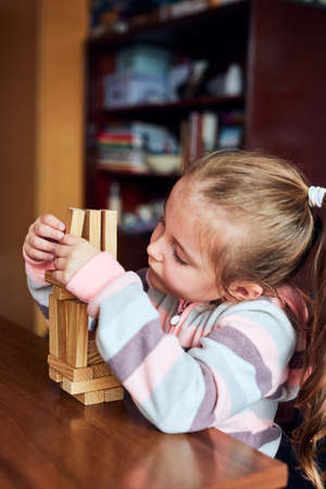 Little girl preschooler playing with wooden blocks toy building a tower. Concept of building a houseの写真素材