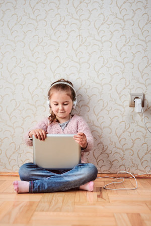 Little girl preschooler learning online solving puzzles playing educational games listetning to...