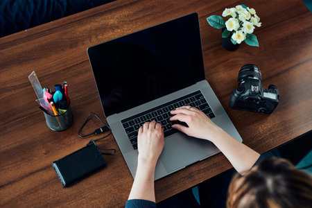 Female photographer working on photos on laptop and camera. Woman editing retouching browsing photos...