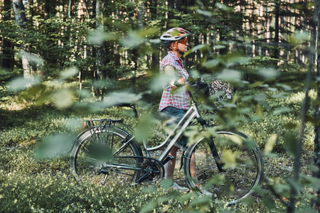 Active woman spending free vacation time on a bicycle trip in a forest on sunny summer day. Woman...