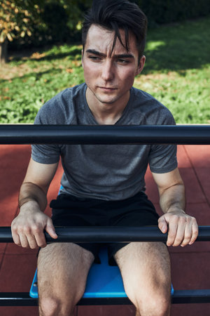 Portrait of young man having break during his workout in a modern calisthenics street workout park....