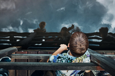 View from above of boy looking down at lake water surfaceの写真素材