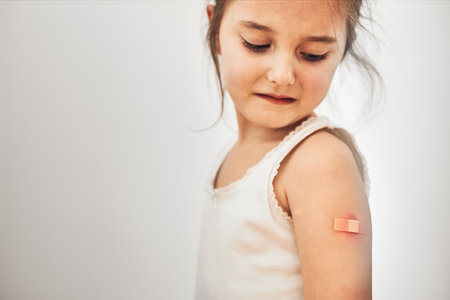 Little girl feeling pain having some side effects after vaccination. Redness, swelling, aching limbs and headache as reaction after vaccination. Getting a first injection. Healthy and medical conceptの写真素材