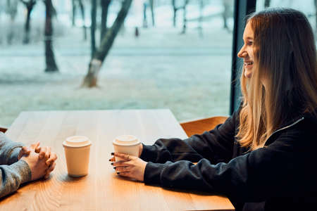 Friends having a chat, talking together, drinking coffee, sitting in a cafe. Young man and woman having a break, relaxing in cafeの写真素材