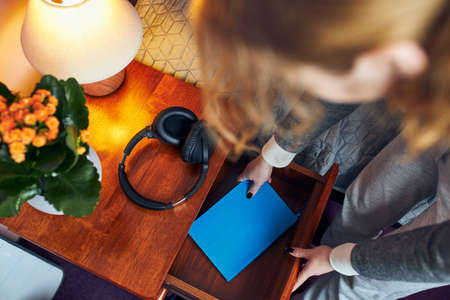 Young woman pulling diary from bedside drawer. Writing journal. Making personal notesの写真素材