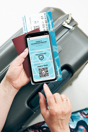 Digital covid certificate. Covid negative rapid digital test pass. Woman passenger holding digital medical pass on her mobile phone, passport and airplane ticket. Traveler showing digital covid test result as medical pass for travel during covid-19 pandemicの写真素材