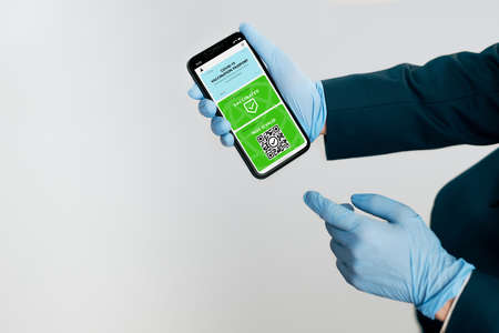 Digital covid certificate. Covid negative rapid digital test pass. Woman passenger holding digital medical pass on her mobile phone, passport and airplane ticket. Traveler showing digital covid test result as medical pass for travel during covid-19 pandemicの写真素材