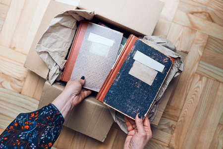 Woman taking books out of cardboox. Unpacking parcel. Female hands holding booksの写真素材