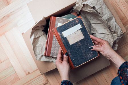 Woman taking books out of cardboox. Unpacking parcel. Female hands holding booksの写真素材
