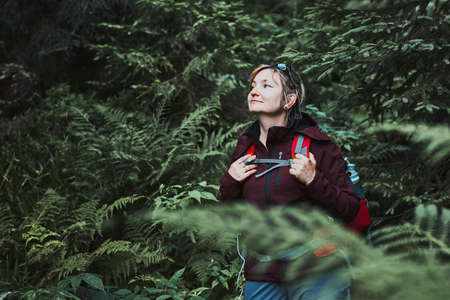 Woman with backpack hiking in forest, actively spending summer vacation close to nature. Woman walking on path among treesの写真素材
