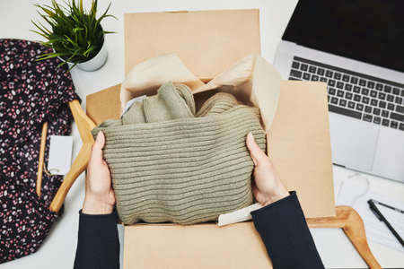 Packing online order to delivery to customer. Preparing parcel box with clothes product from online shopの写真素材