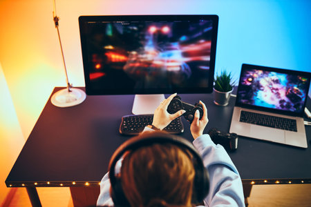 Teenager girl playing video game at home. Gamer holding gamepads sitting at front of screen....