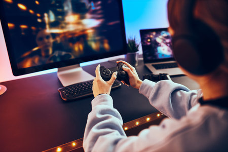 Teenager girl playing video game at home. Gamer holding gamepads sitting at front of screen....