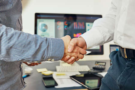 Handshake of business people. Man and woman shaking hands in office. Two people greeting at work. Collaborative teamworkの写真素材