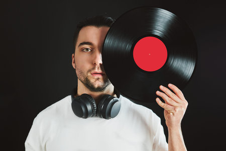 Man holding retro vinyl record covering face. Vintage music style. Male holding vinyl record disc...