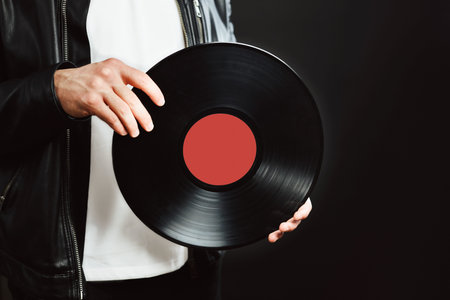 Man with vinyl record. Vintage music style. Rock style. Male wearing black jacket holding turntable...