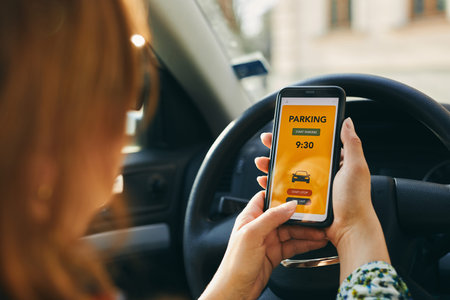 Woman using mobile parking app on smartphone. Driver using smartphone to pay for parking. Car park...