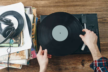 Man listening to music from vinyl record. Playing music from analog disk on turntable player. Enjoying music from old collection. Relaxing at home. Retro and vintage. Music passionの写真素材